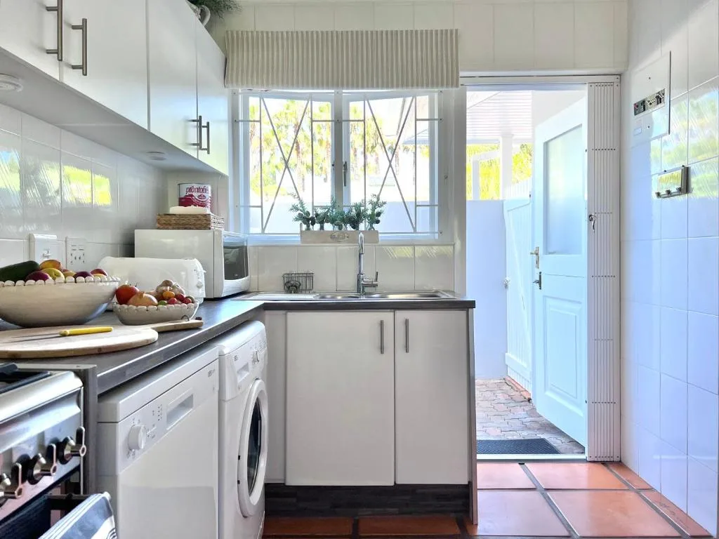 Bright modern kitchen with white cabinetry, stainless steel appliances, and garden views