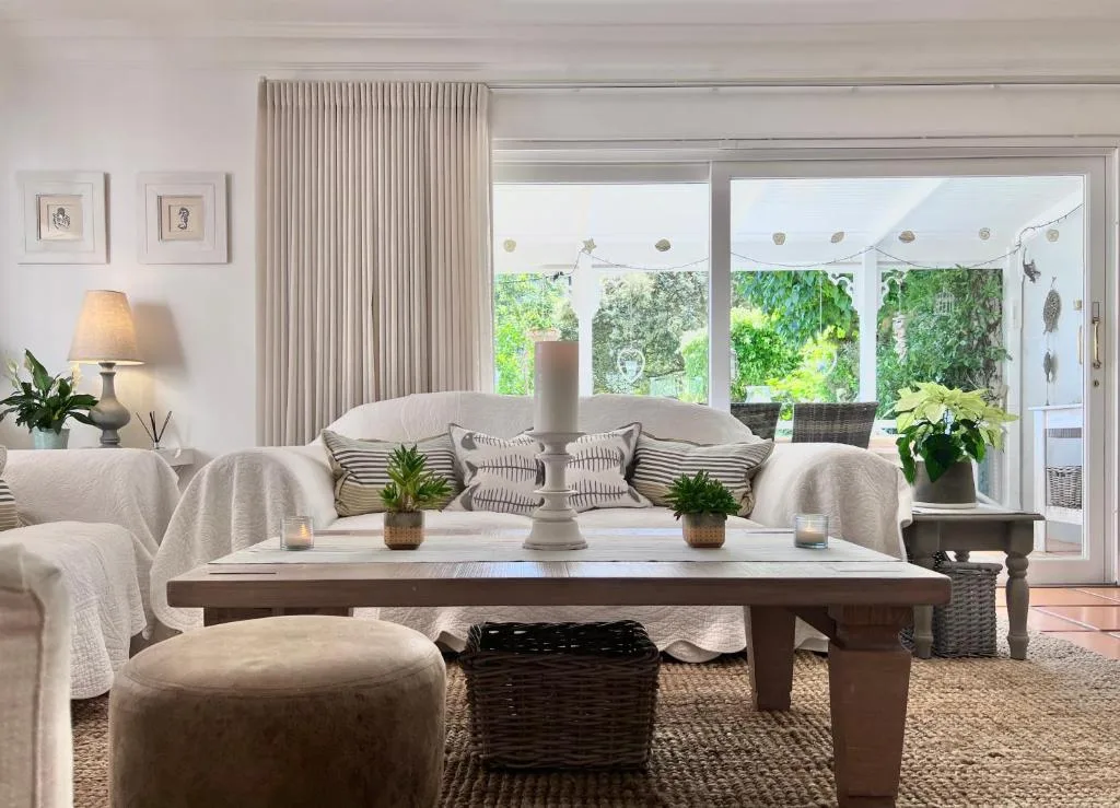 Bright lounge with cream sofa, wooden coffee table, garden views through glass doors