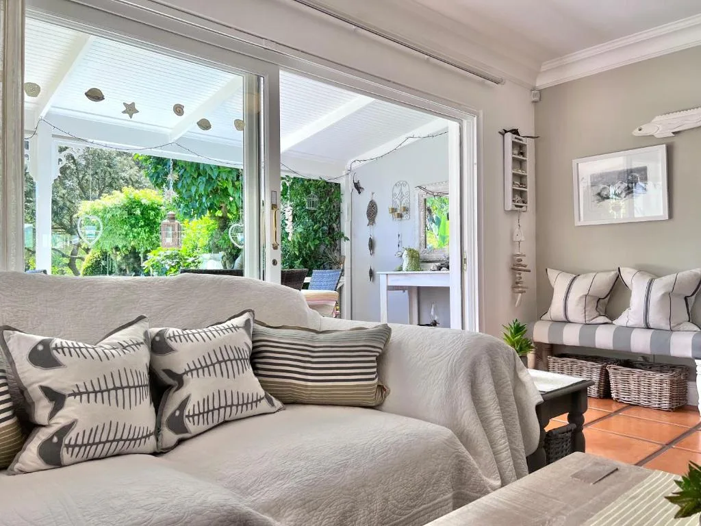 Bright living room with grey sofa, patterned cushions, opens to garden views