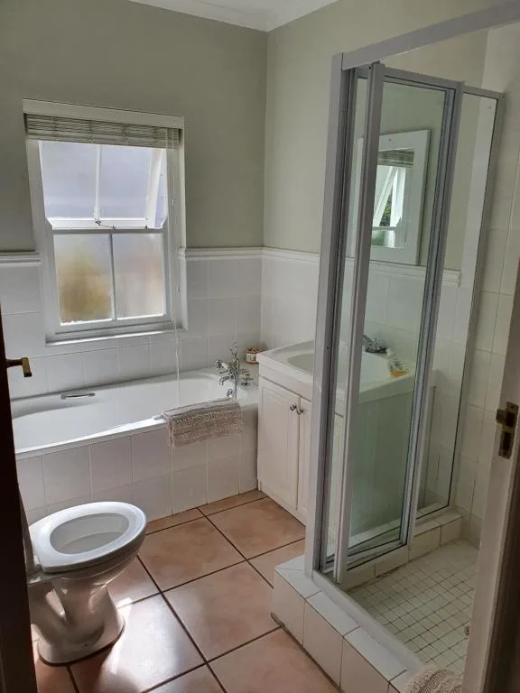 Bathroom with toilet, bathtub, corner shower, and window with natural light