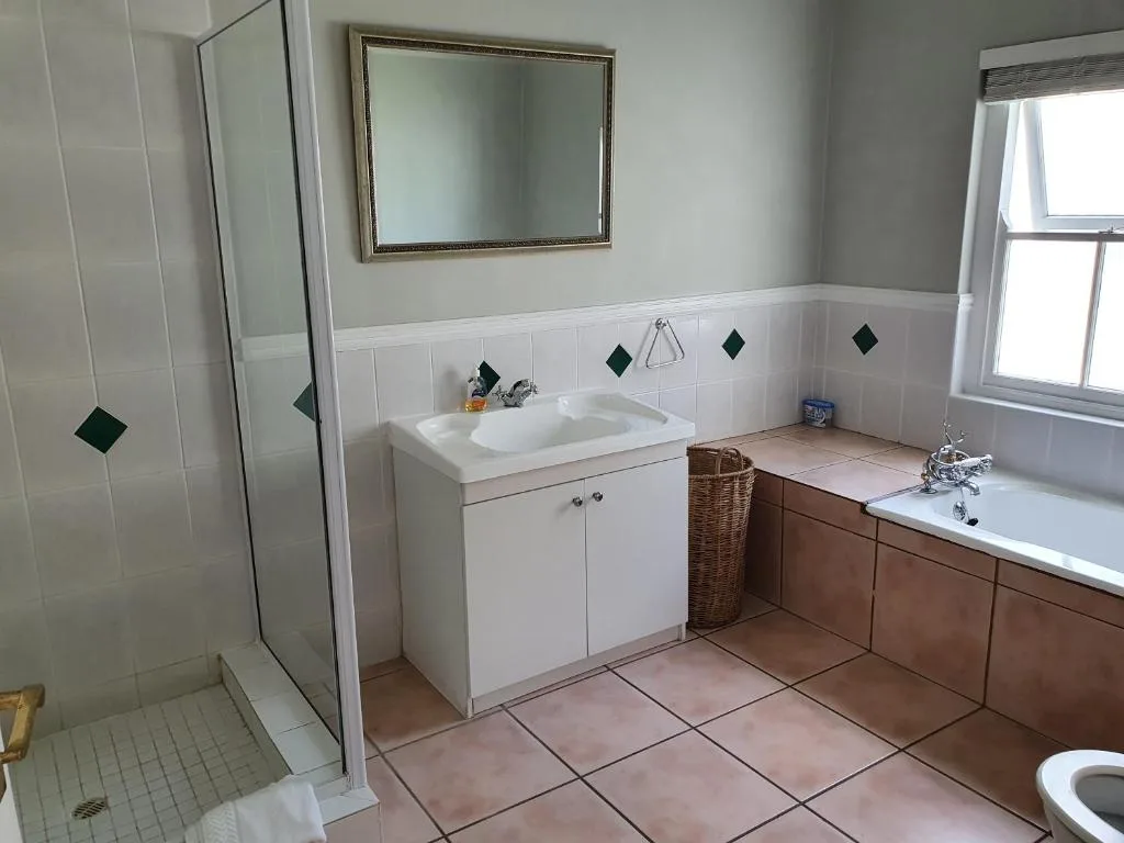 Spacious bathroom with vanity, bathtub, shower, and framed mirror