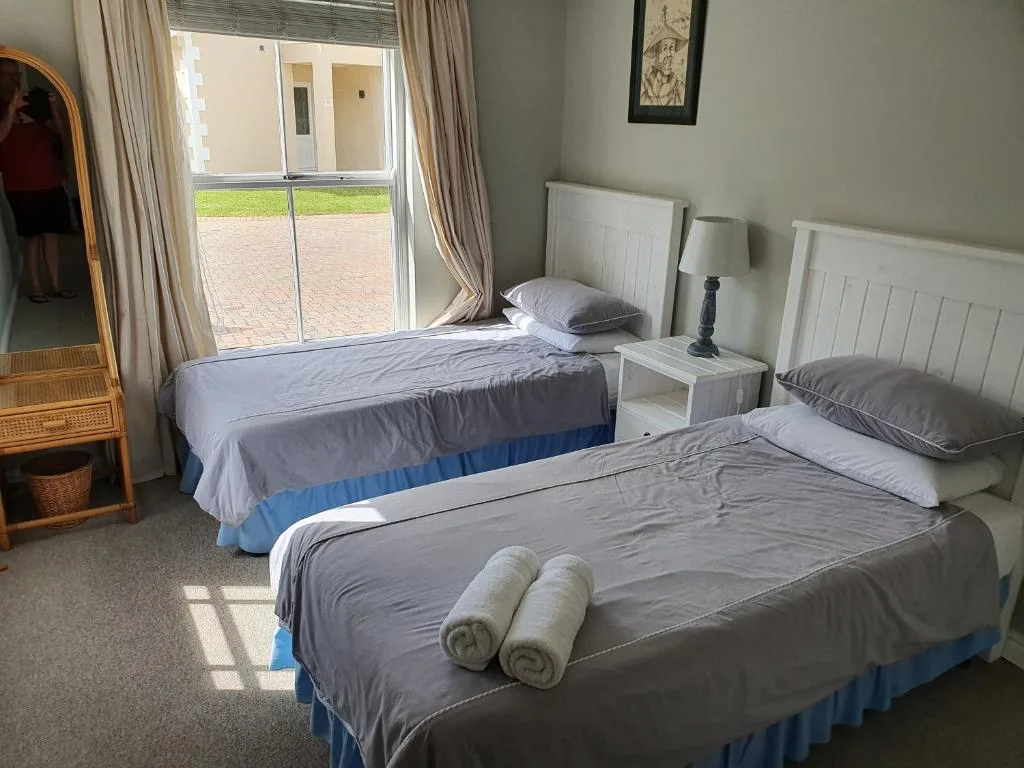 Twin bedroom with white headboards, rolled towels, and garden view doors