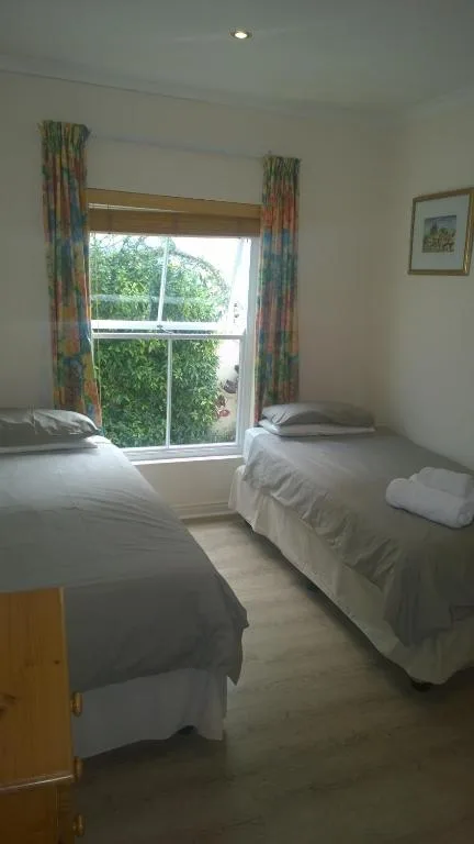 Bright bedroom with two single beds and large window overlooking garden
