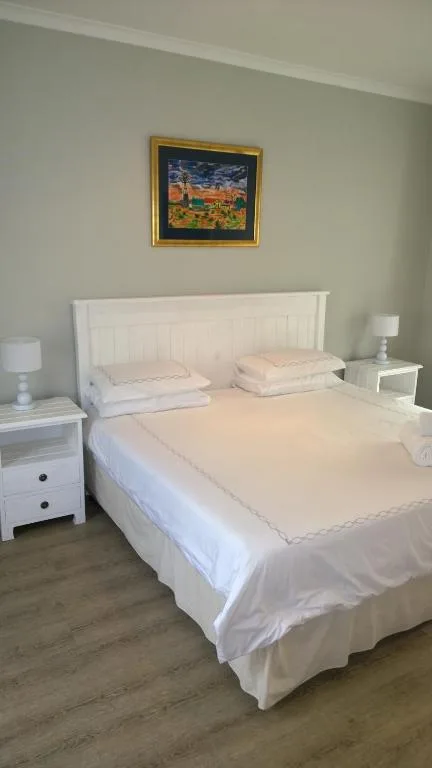 Spacious bedroom with white bed, nightstands, and framed artwork on wall