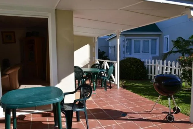 Covered patio with green table, chairs, and braai grill