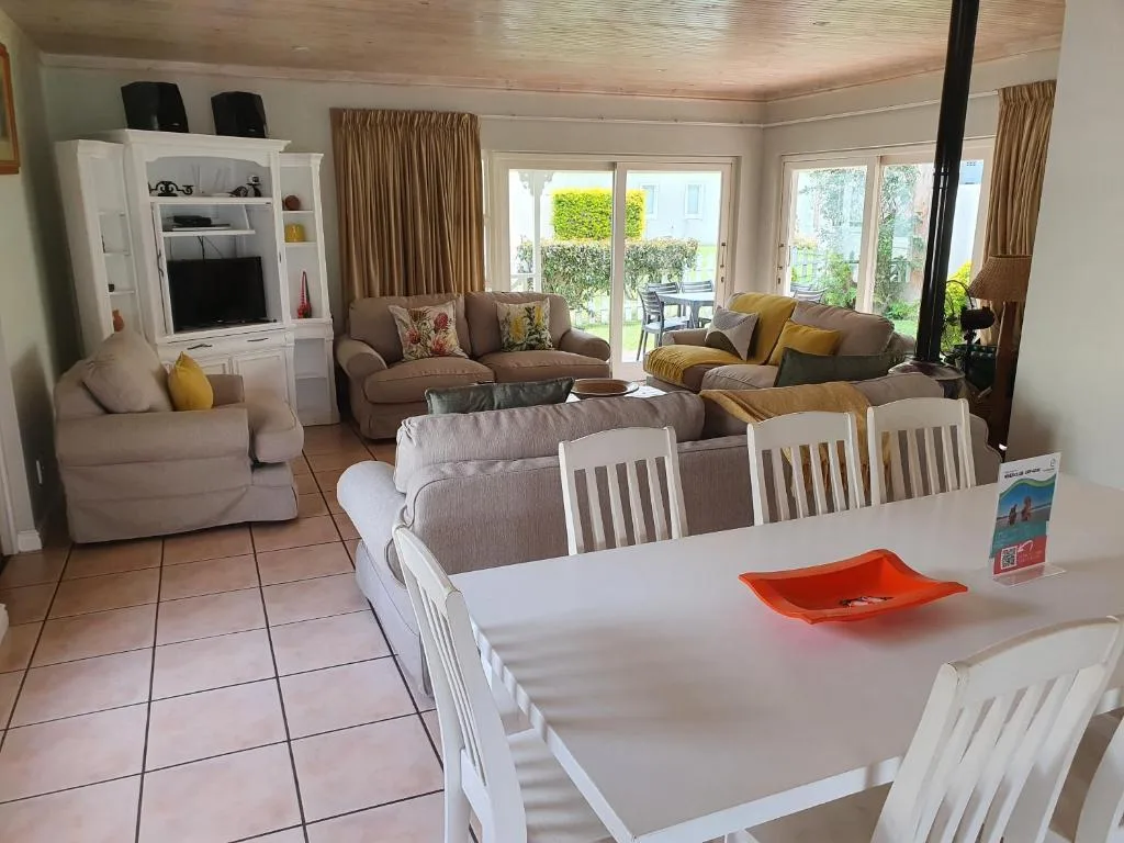 Open-plan dining and lounge area with white chairs and garden views