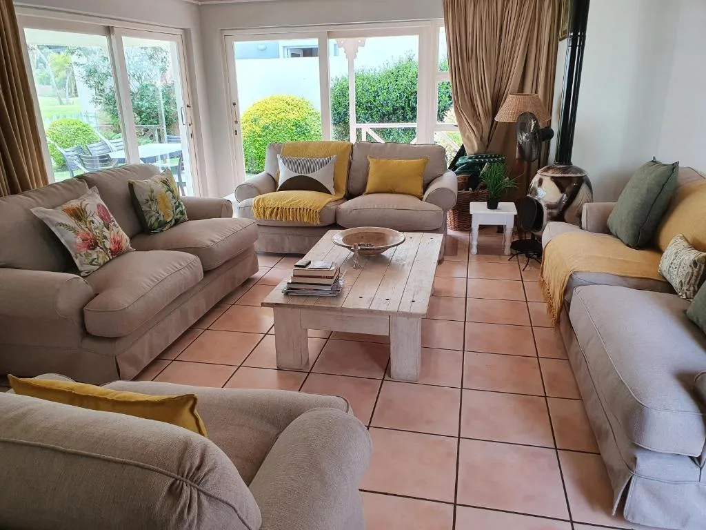 Spacious lounge with beige sofas, terracotta tiles, garden views through glass doors