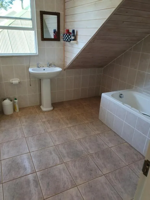 Spacious bathroom with pedestal sink, bathtub, and tiled flooring