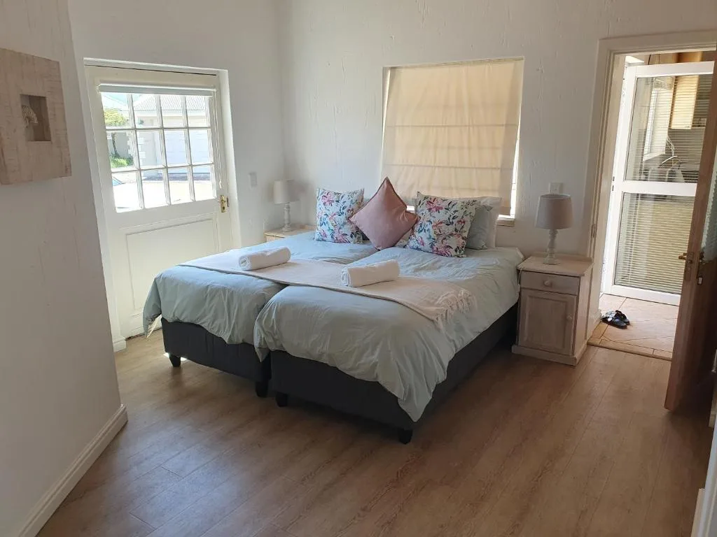 Bright bedroom with queen bed, floral pillows, and ocean view doors