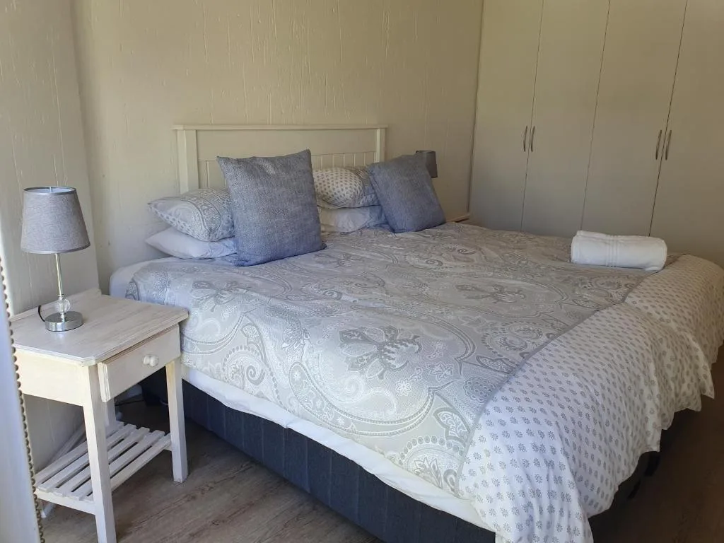 Bright bedroom with queen bed, blue pillows, white bedding, and bedside lamp
