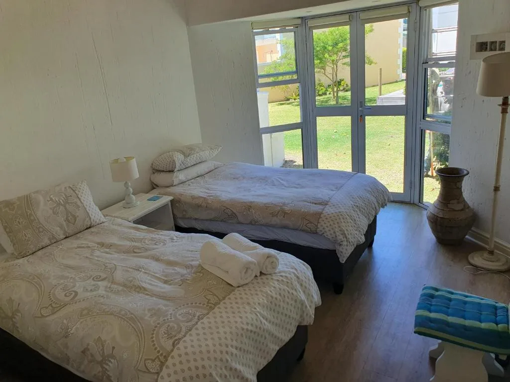 Bright bedroom with two beds, garden views through glass doors