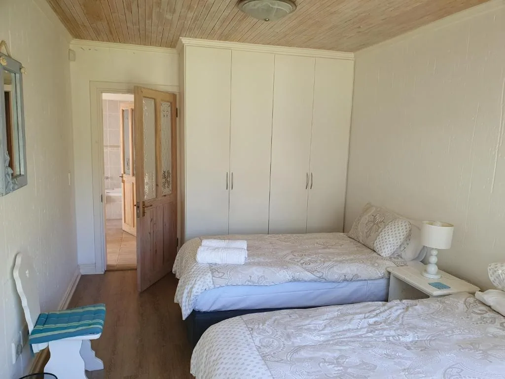Bright bedroom with two beds, built-in wardrobes, wooden ceiling
