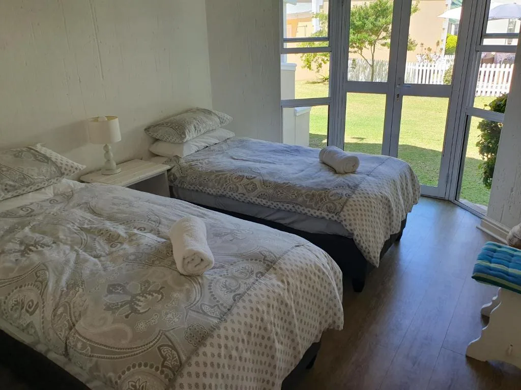 Twin bedroom with garden views through large patio doors and lawn beyond