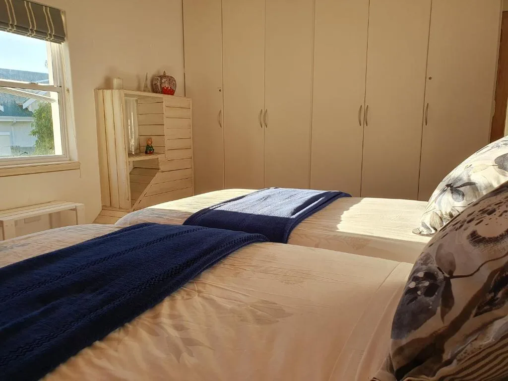 Bright bedroom with double bed, navy blankets, and built-in wardrobes