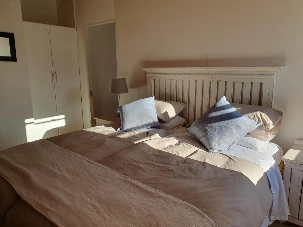 Bright bedroom with white wooden headboard and neatly arranged pillows