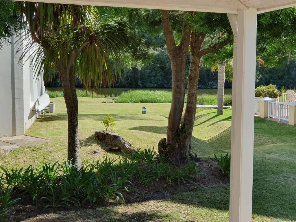 Covered patio with manicured lawn and mature trees beyond