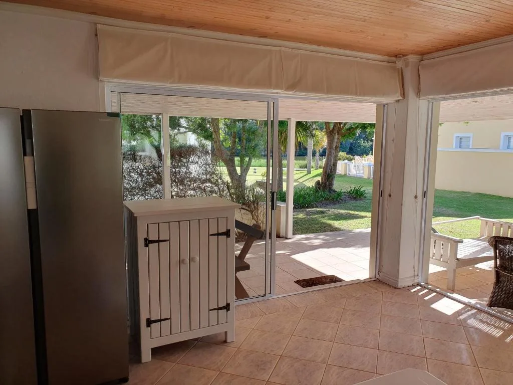 Covered patio area with glass doors opening to manicured garden and lawn