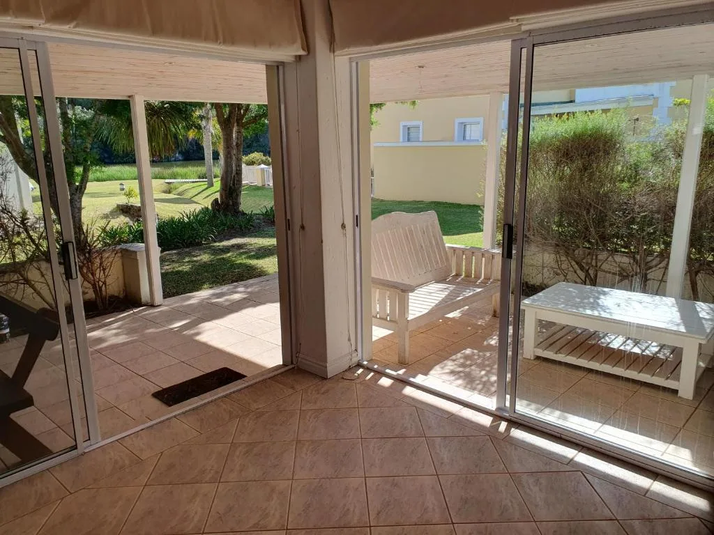 Covered patio area with white chair overlooking manicured garden and lawn