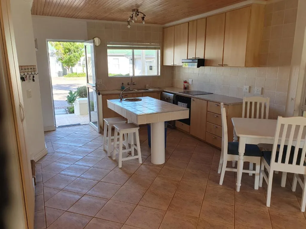 Open-plan kitchen with wooden cabinetry, blue-tiled island counter, and dining chairs