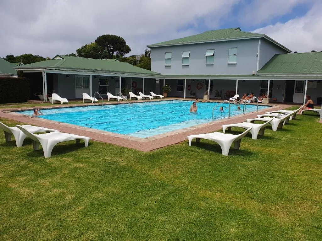 Large sparkling swimming pool with lounge chairs and manicured lawn surroundings