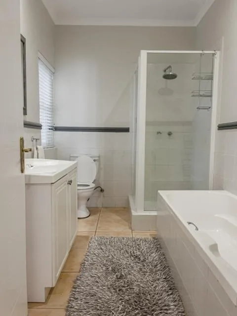 Modern bathroom with white vanity, toilet, shower enclosure, and bathtub