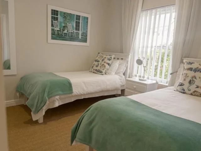 Bright bedroom with two single beds and green bedding, large window