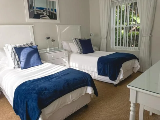 Bright twin bedroom with blue velvet throws and white bedside tables