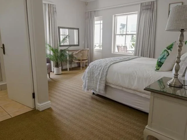 Bright bedroom with queen bed, large windows overlooking garden, comfortable furnishings