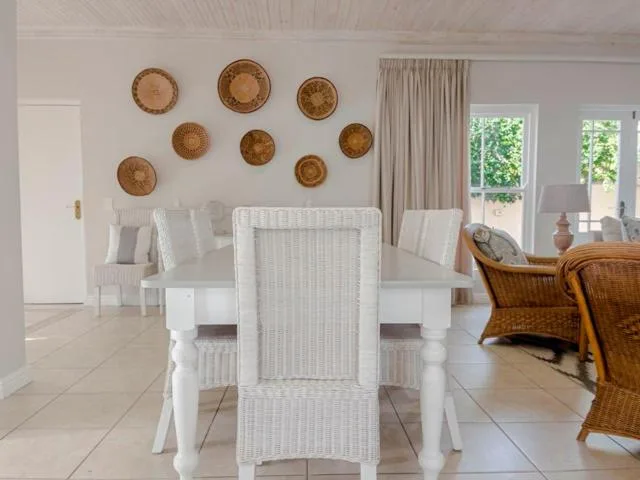 Bright dining area with white table, wicker chairs, and decorative wall baskets