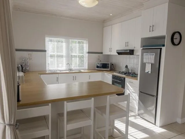 Modern kitchen with white cabinetry, wooden countertops, and dining table