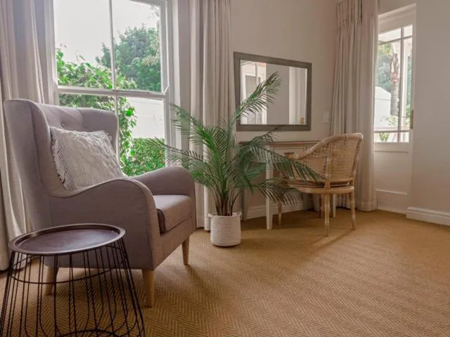 Bright lounge with comfortable armchair, potted plant, and garden views