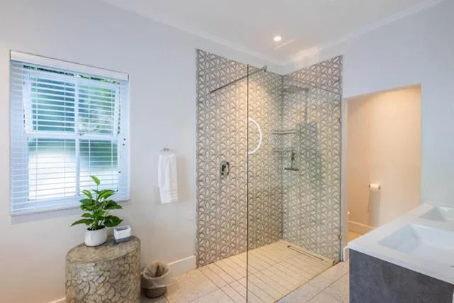 Modern bathroom with frameless glass shower enclosure and geometric tile pattern