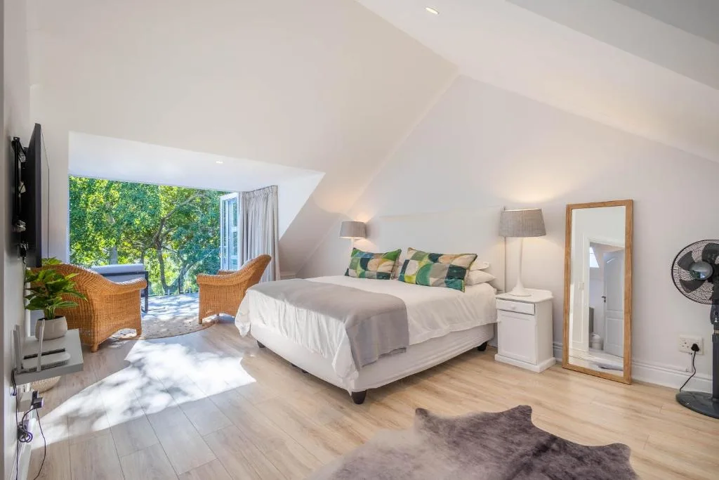 Bright bedroom with queen bed, wicker chairs, and garden view doors