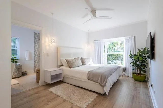 Bright bedroom with queen bed, pendant lights, and garden view doors