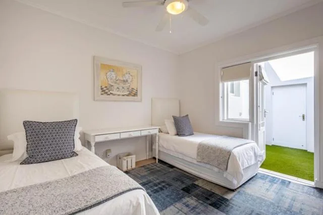 Twin bedroom with two single beds, white bedding, and access to outdoor patio area