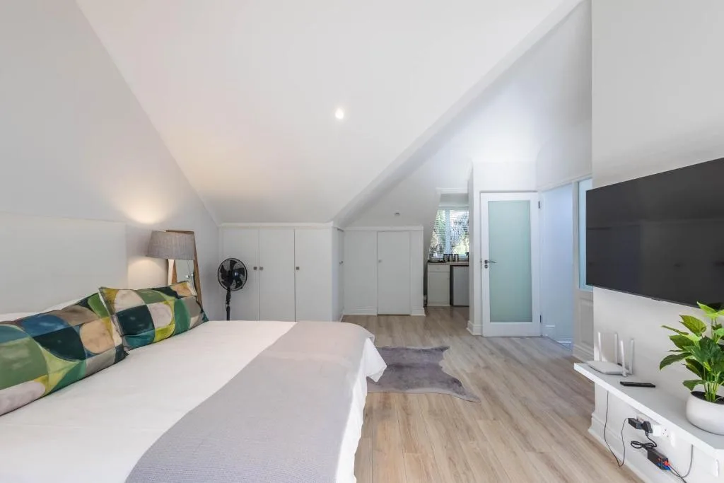 Spacious bedroom with queen bed, built-in wardrobes, and ensuite access