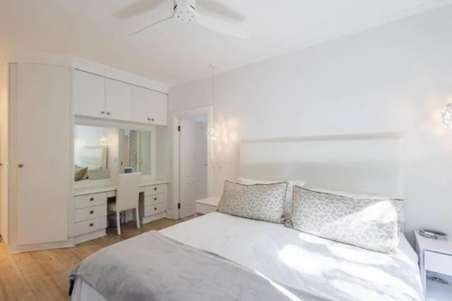 Bright bedroom with queen bed, white built-in wardrobe and vanity mirror