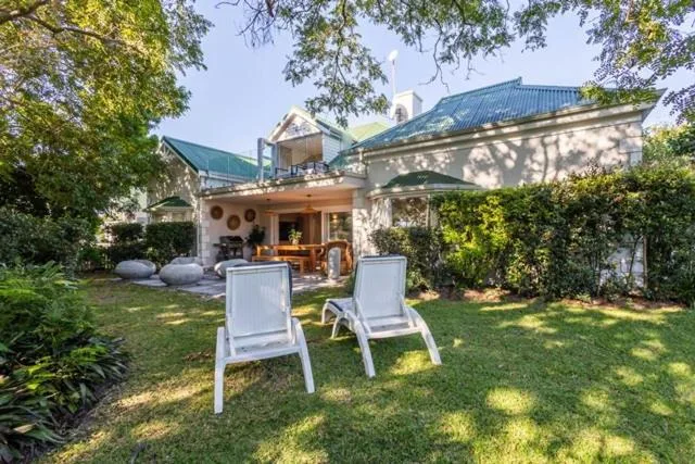 Shaded lawn with white lounge chairs facing the property exterior