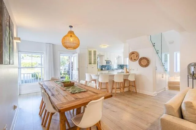 Open-plan dining area with wooden table and cream chairs, pendant lighting