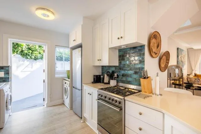 Modern kitchen with white cabinetry, gas range, and teal tile backsplash