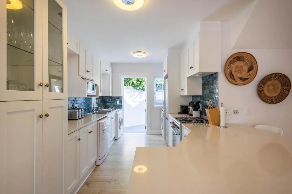 Modern kitchen with white cabinetry, blue tile backsplash, and stainless steel appliances
