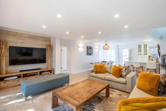Bright lounge with sofas, TV, wooden table, and yellow accent pillows