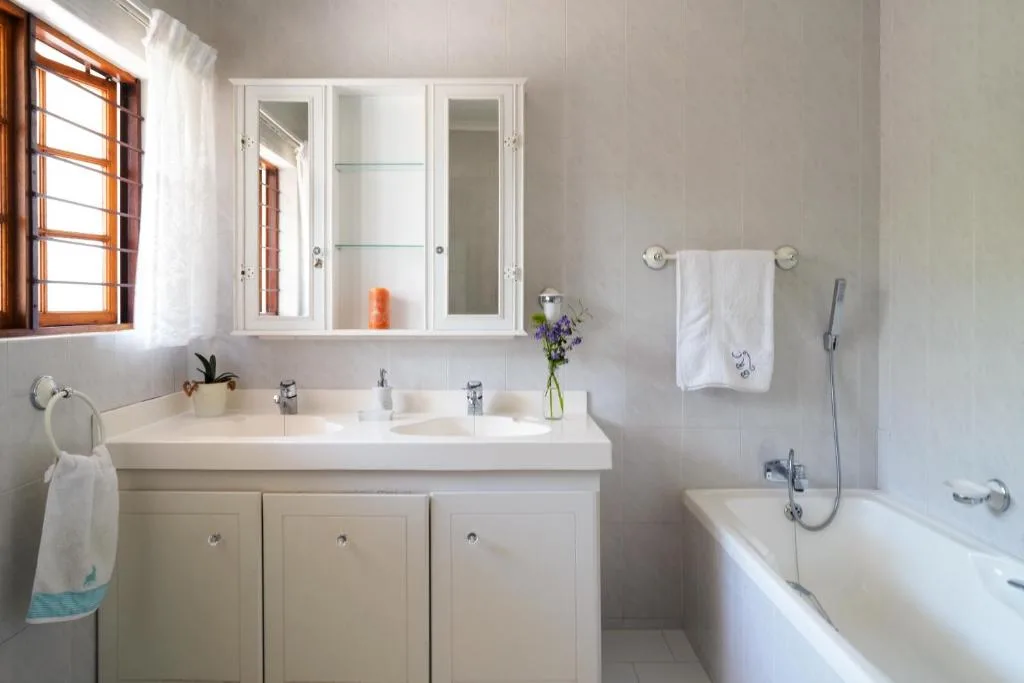 Bright bathroom with double vanity, mirrored cabinet, and soaking tub
