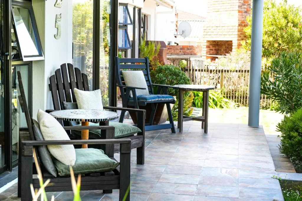 Covered patio with black Adirondack chairs and garden views