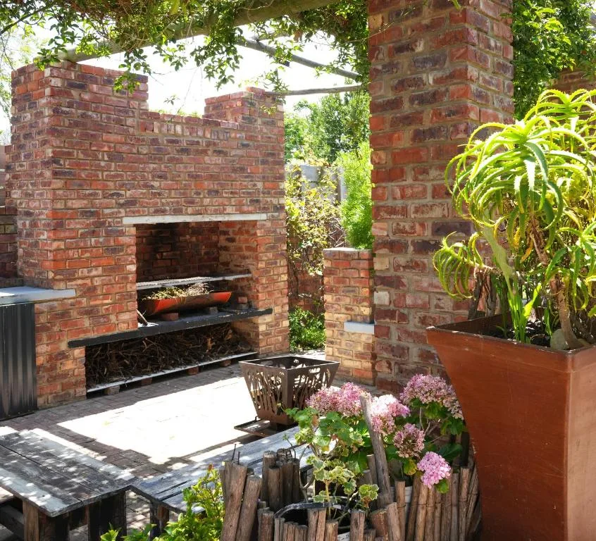 Brick braai area with plants and garden seating on paved patio