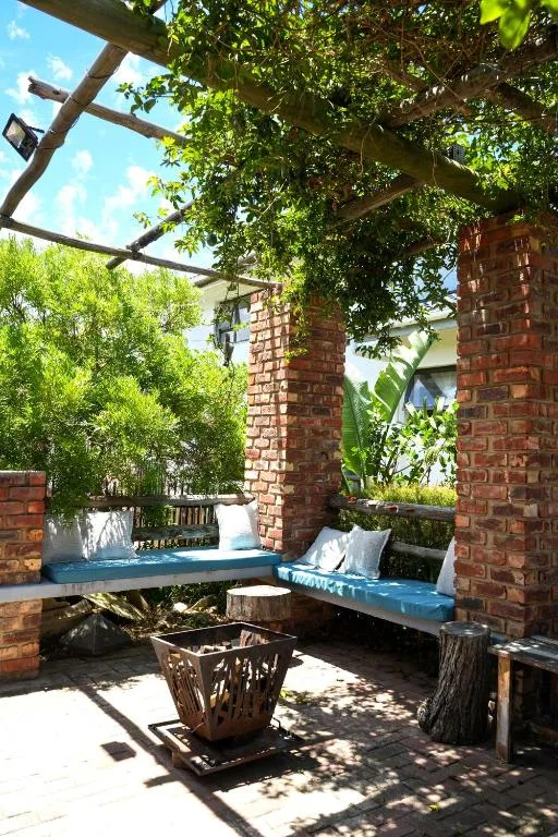 Shaded outdoor seating area with blue bench and cushions under pergola