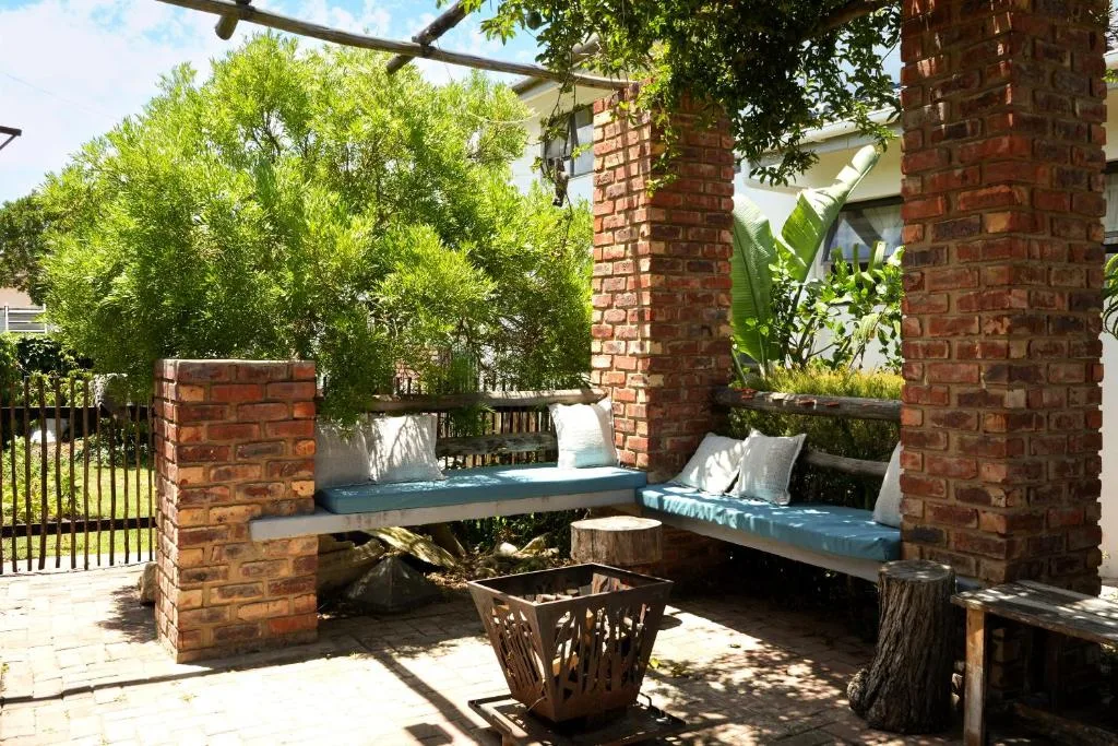 Shaded brick pergola seating area with blue cushions and potted plants