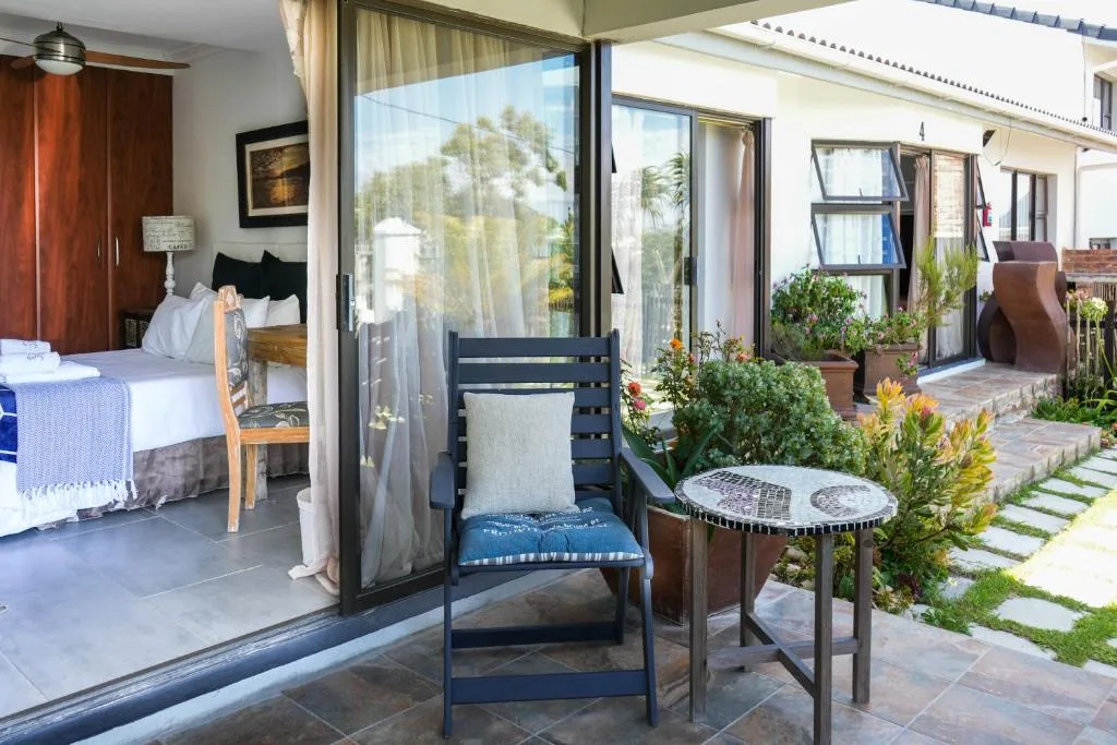 Outdoor patio with black chair, small table, potted plants, and bedroom access