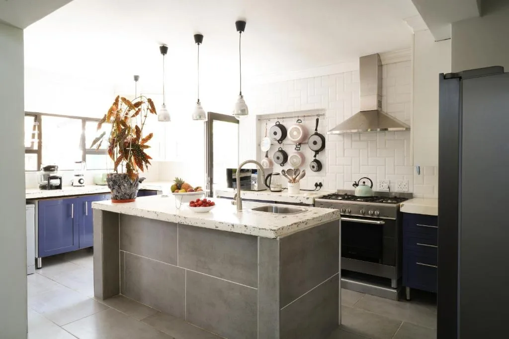 Modern kitchen with island, marble countertop, stainless steel appliances, pendant lights