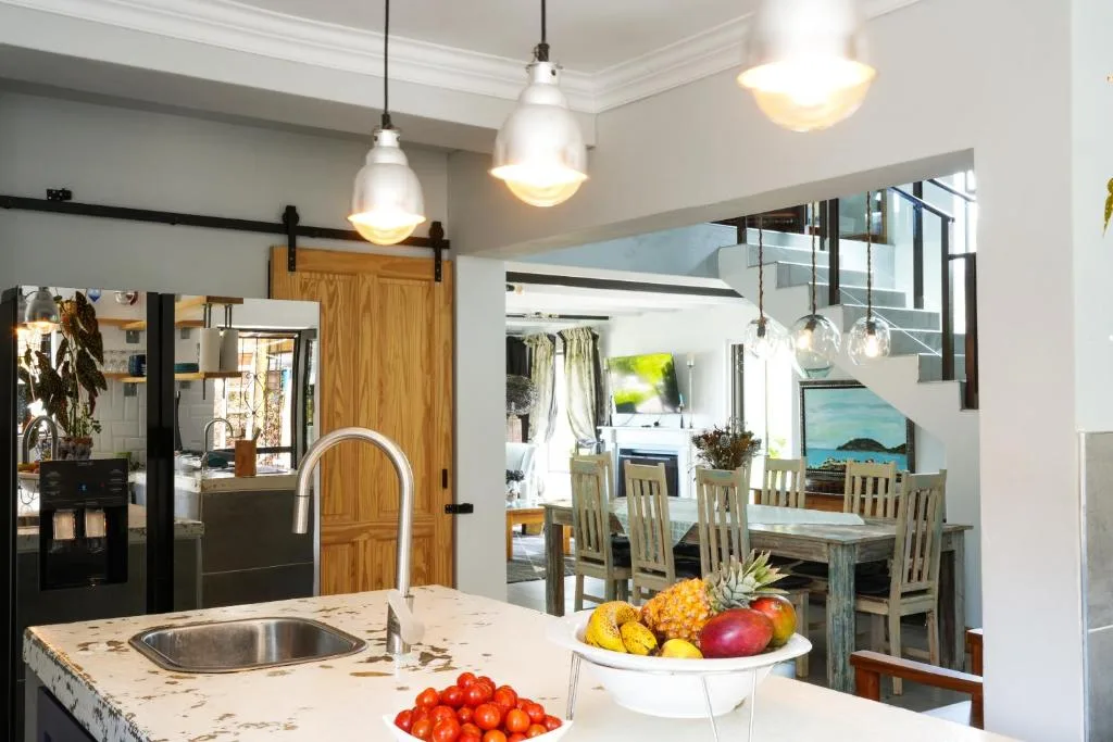Modern kitchen with pendant lights, marble countertop, and open-plan dining area view